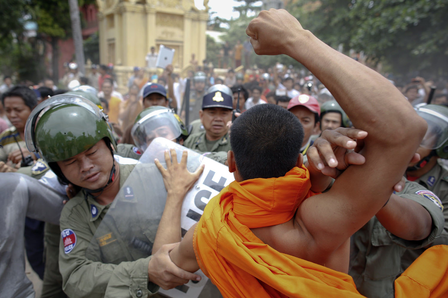 July 28, 2013. Riot policemen protect a man, that was accused of trying to hit a Buddhist monk, as a monk tries to punch him after an incident at a polling station in which voters protested against alleged election irregularities in Phnom Penh, Cambodia.