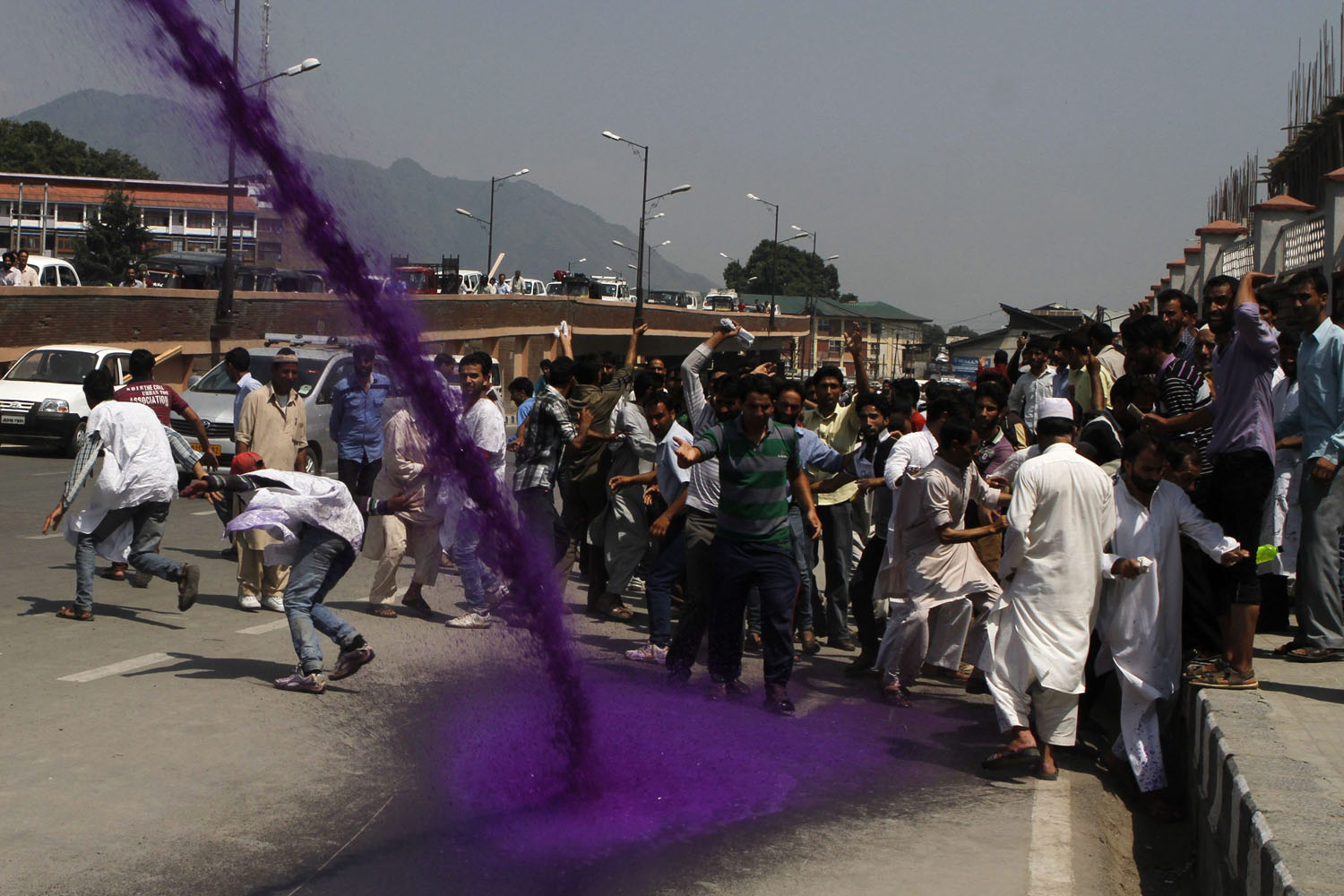July 29, 2013. Government employees and Indian policemen run as police spray purple water during protests in Srinagar, the summer capital of Indian Kashmir.