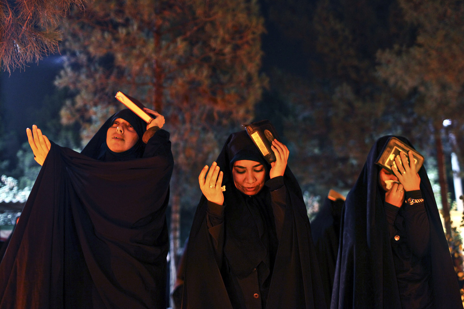 July 30, 2013. Iranian women place copies of the Quran on their heads as they mourn, during a religious ceremony marking Imam Ali's death at the Behesht-e-Zahra cemetery, just outside Tehran.