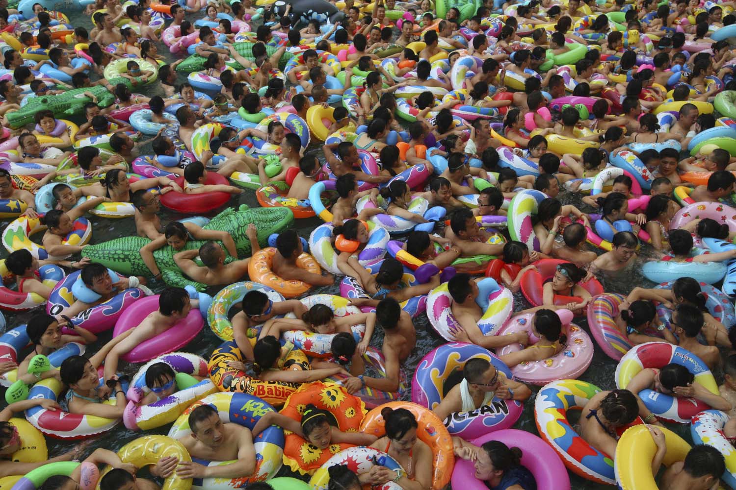 July 27, 2013. Visitors crowd an artificial wave pool at a tourist resort to escape the summer heat in Daying county of Suining, Sichuan province.
