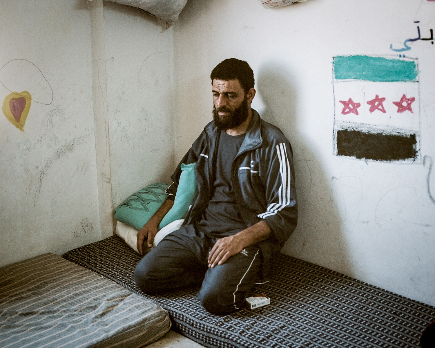 Hamad sits near a hand painted Free Syrian Army flag in his home in the Cyber City refugee camp near Irbid, Jordan.