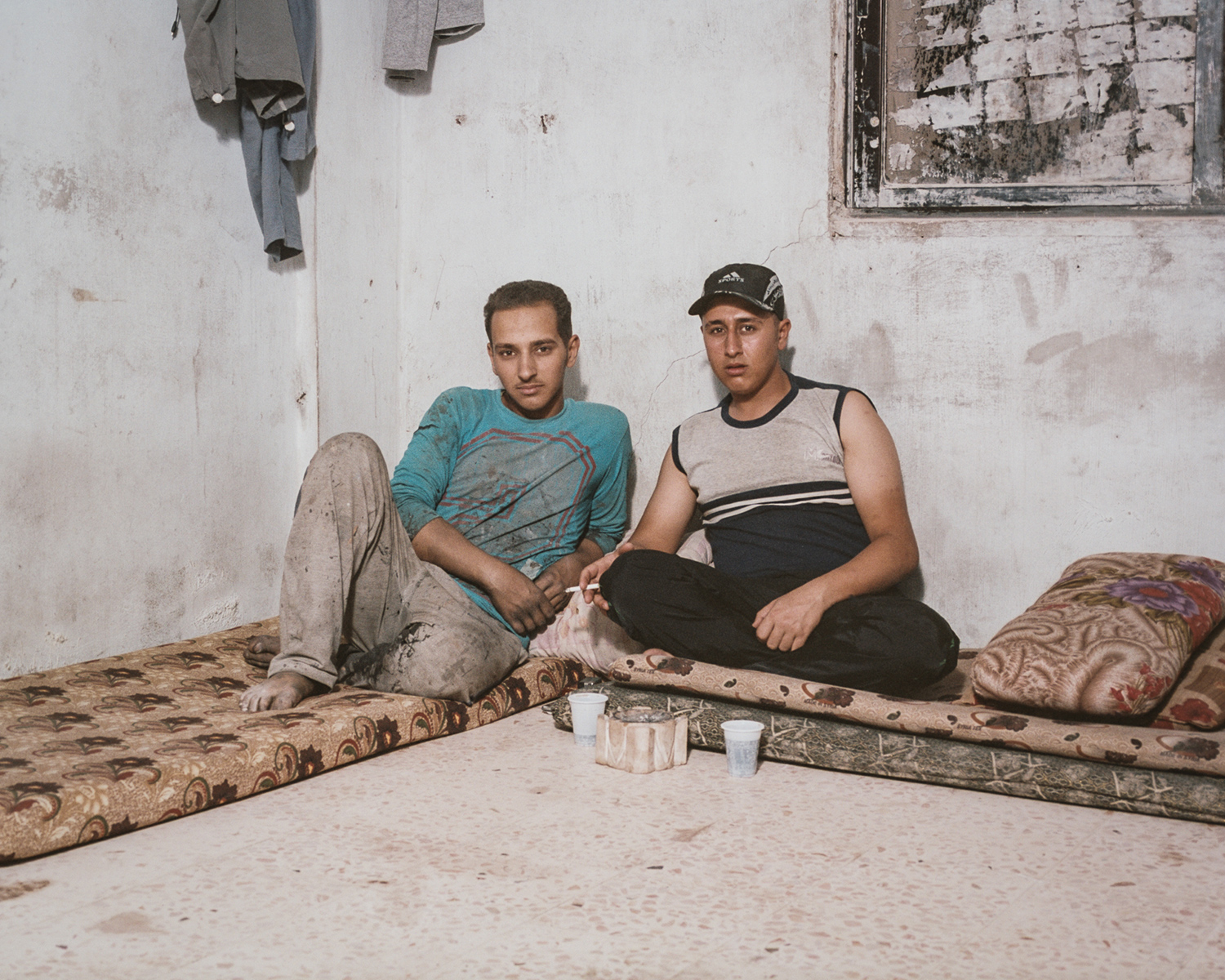 Syrian brothers Eyad and Mo'ayad Ghassan  Al-Jughmani in the room they share with three other foreign laborers in an apartment on the outskirts of Amman, Jordan. Both brothers work as day laborers in the area to earn money for their mother and young siblings, who also fled to Jordan and live elsewhere in the city.