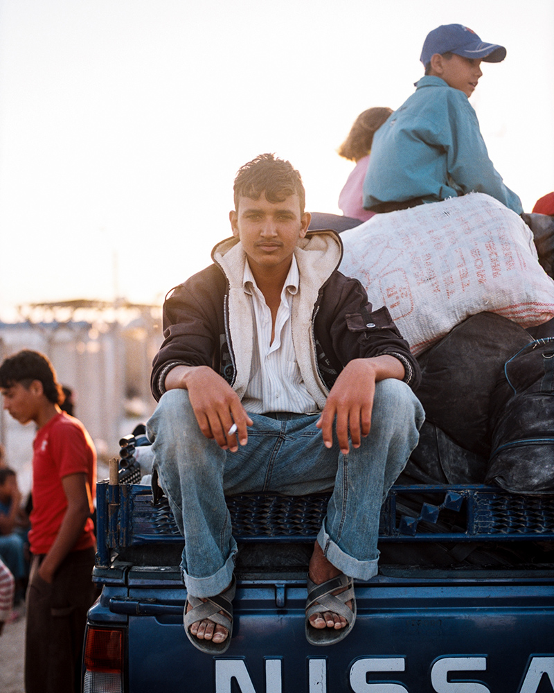 A boy who declined to give his name sits on a truck full of luggage on the outskirts of the Zaatari refugee camp.