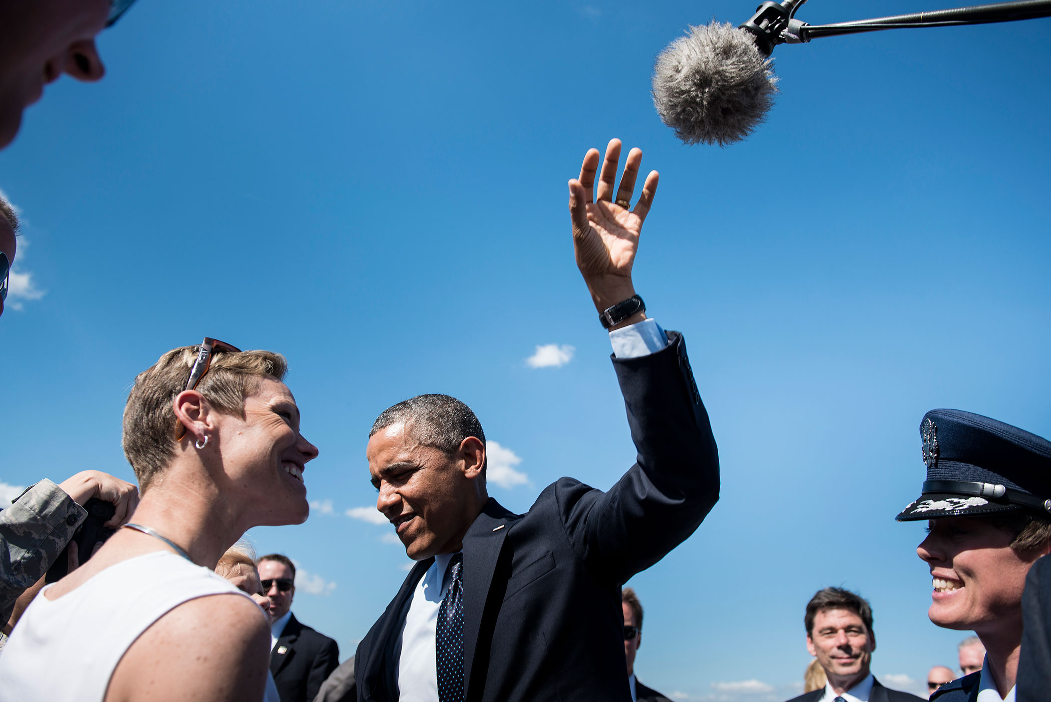 President Barack Obama reaches for a boom microphone while joking with a baby in a crowd of greeters at Whiteman Air Force Base in Missouri, July 24, 2013.