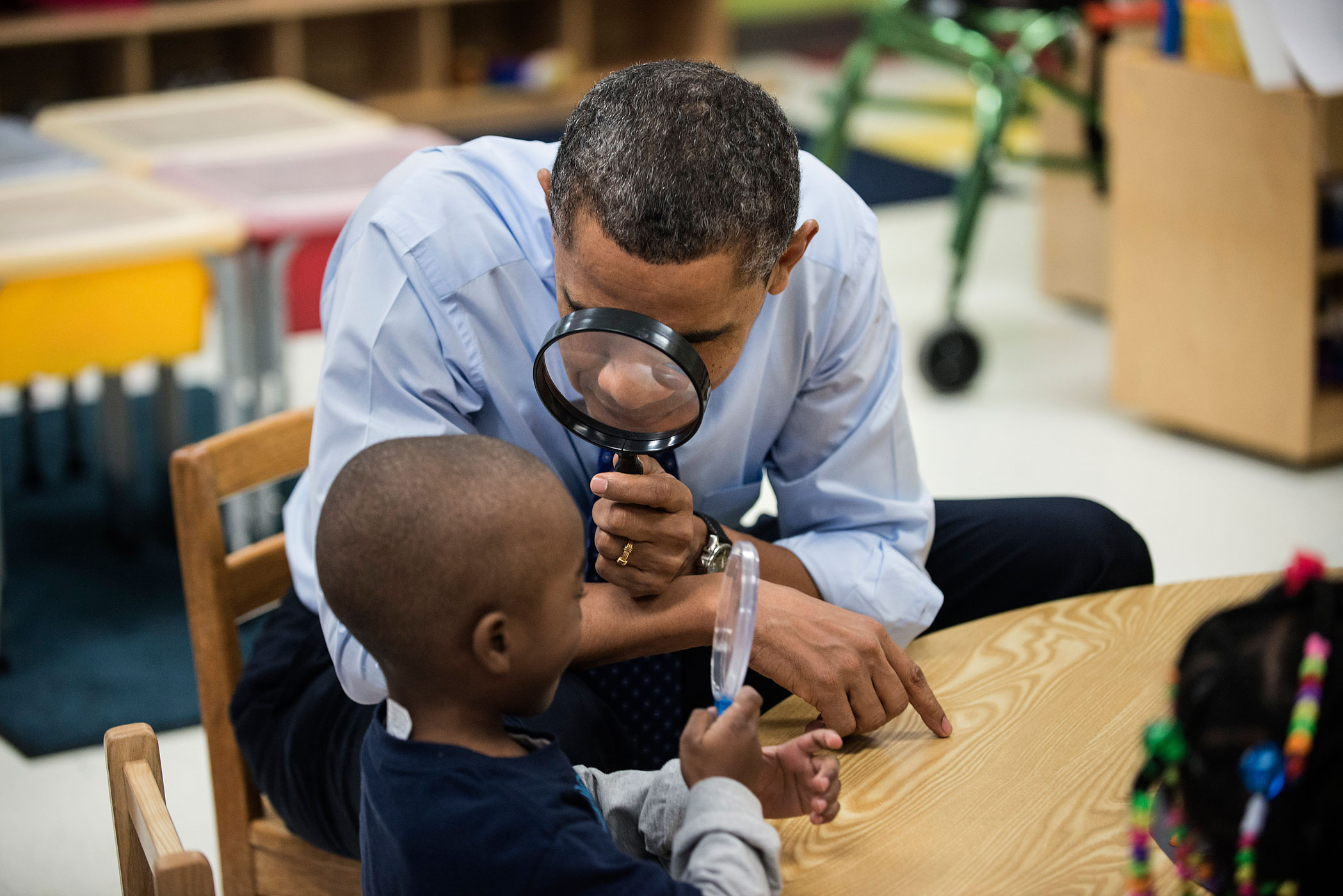 Feb. 14, 2012. President Barack Obama looks at a boy with a magnifying glass while visiting children at College Heights Early Childhood Learning Center in Decatur, Ga.