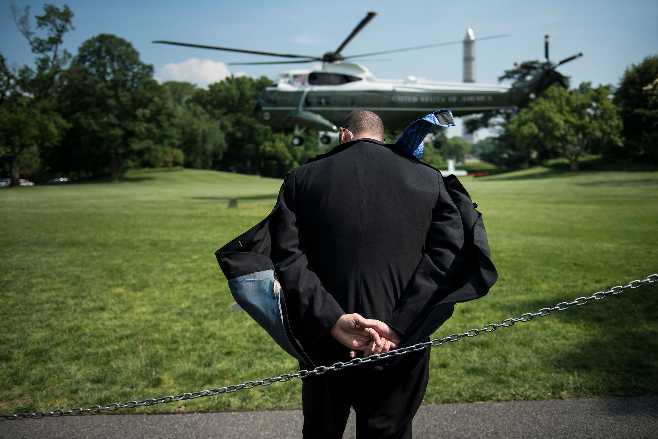 May 29, 2013. A Secret Service agent ducks rotor wash as Marine One lands to pick up President Barack Obama on the South Lawn of the White House in Washington.