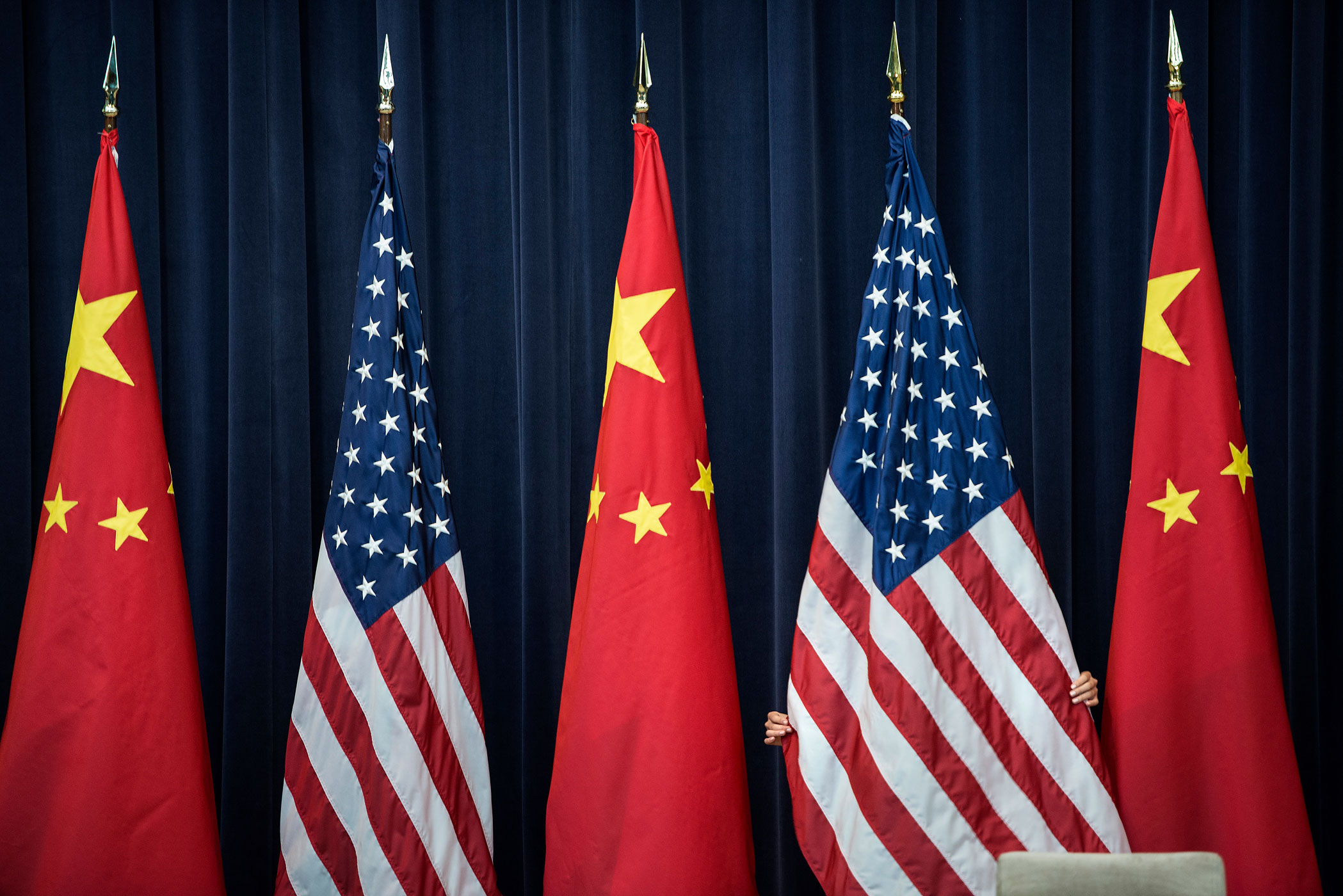 July 10, 2013. A staff member adjusts an American flag before the opening session of the U.S. and China Strategic and Economic Dialogue at the U.S. Department of State in Washington.
