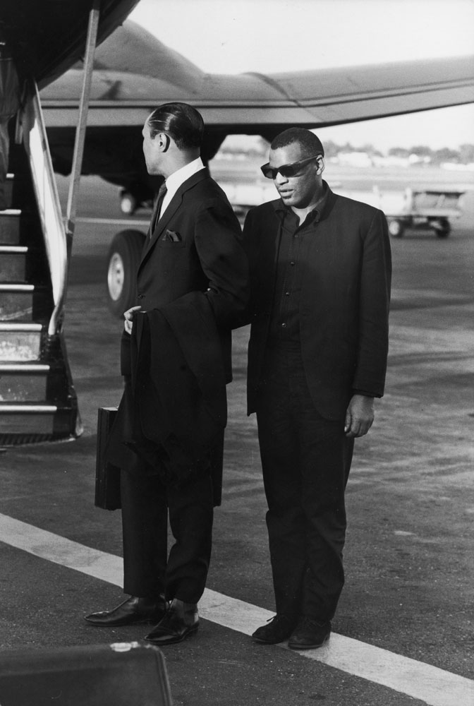 In the early morning at Los Angeles airport, [Ray Charles] waits with his manager, Joe Adams, to board his plane for a flight to New York. His arm is linked to Adams', but Ray still stands very much alone.