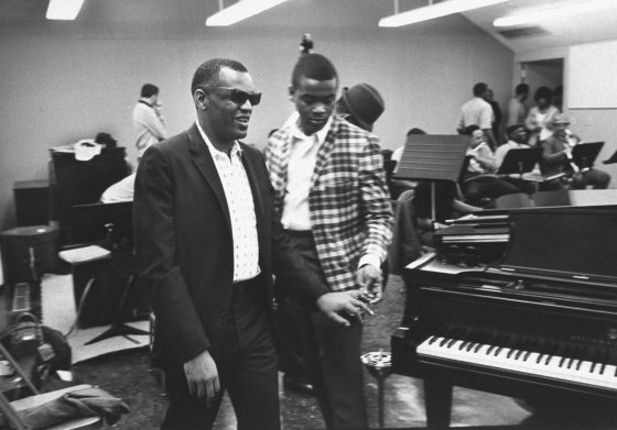 His chauffeur, Vernon Troupe, leads Ray Charles to the piano in Los Angeles studio where Charles records for his own company, named Tangerine after his favorite fruit.