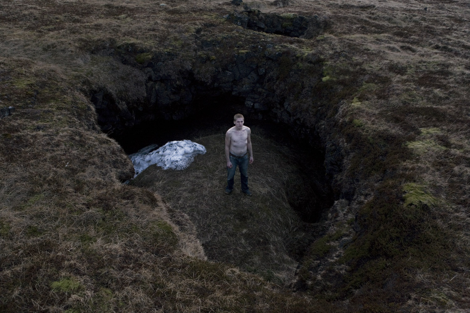 Man standing in one of many mysterious ‘holes’ in the ground in the Snaefellsnes peninsula (home to the volcano that Jules Verne based his novel Journey to the Center of the Earth on). These holes are often several meters in diameter and in depth, creating sunken impressions on the landscape. Iceland, 2011.