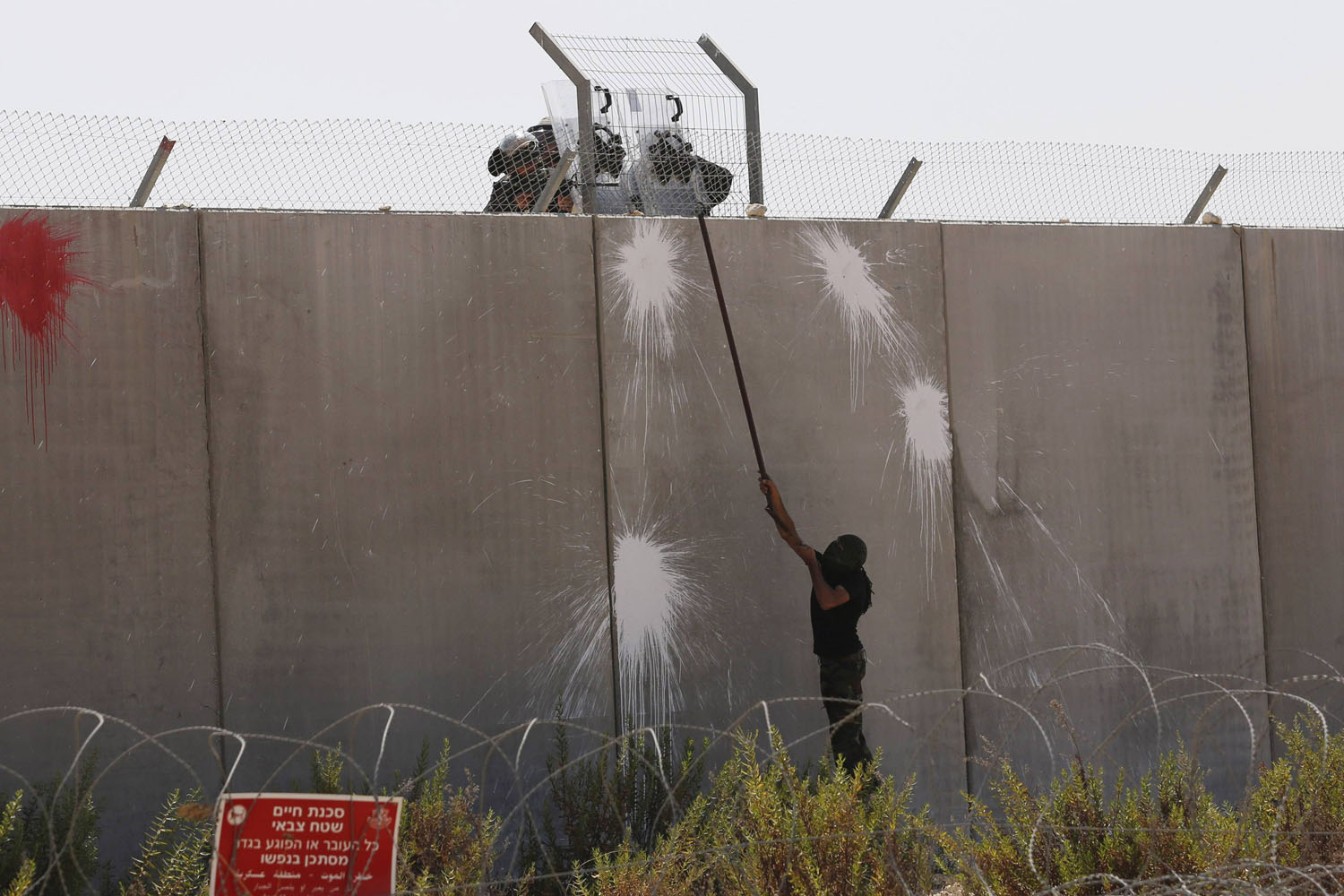A Palestinian protester uses a metal rod at the controversial Israeli barrier during clashes with Israeli border policemen after a protest in Bilin