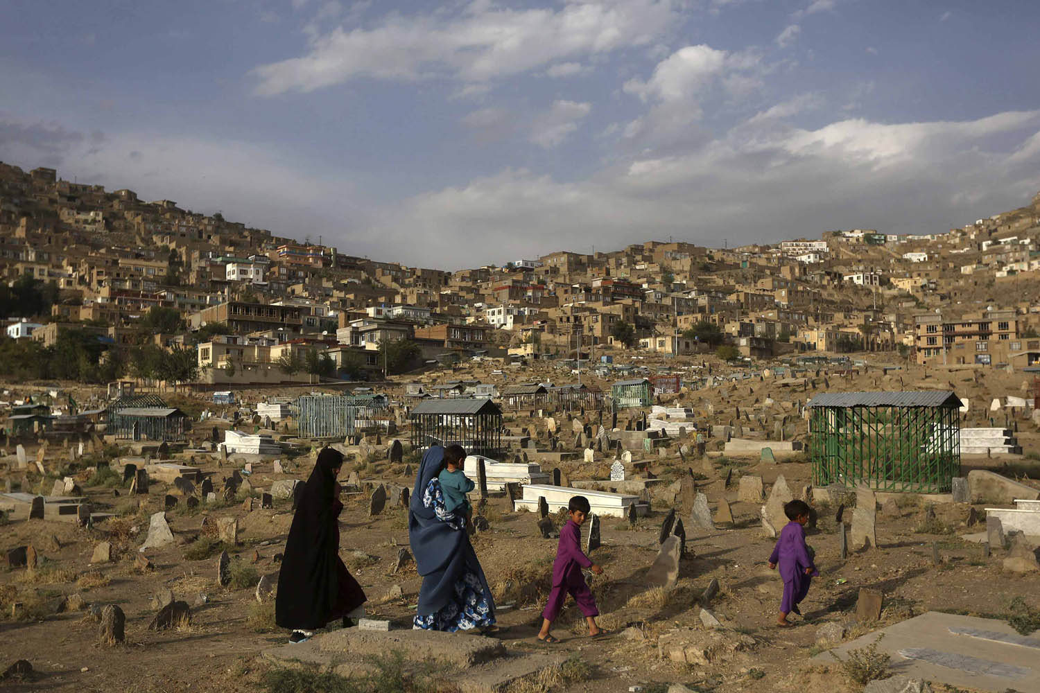 A family walks through a cemetery in Kabul