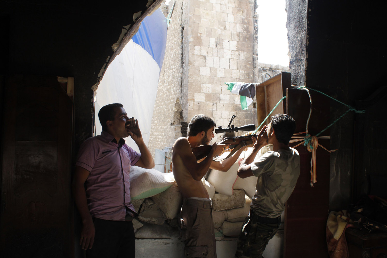 Free Syrian Army fighters call out to forces loyal to Syria's President Assad urging them to defect as another fighter stands guard in the old city of Aleppo