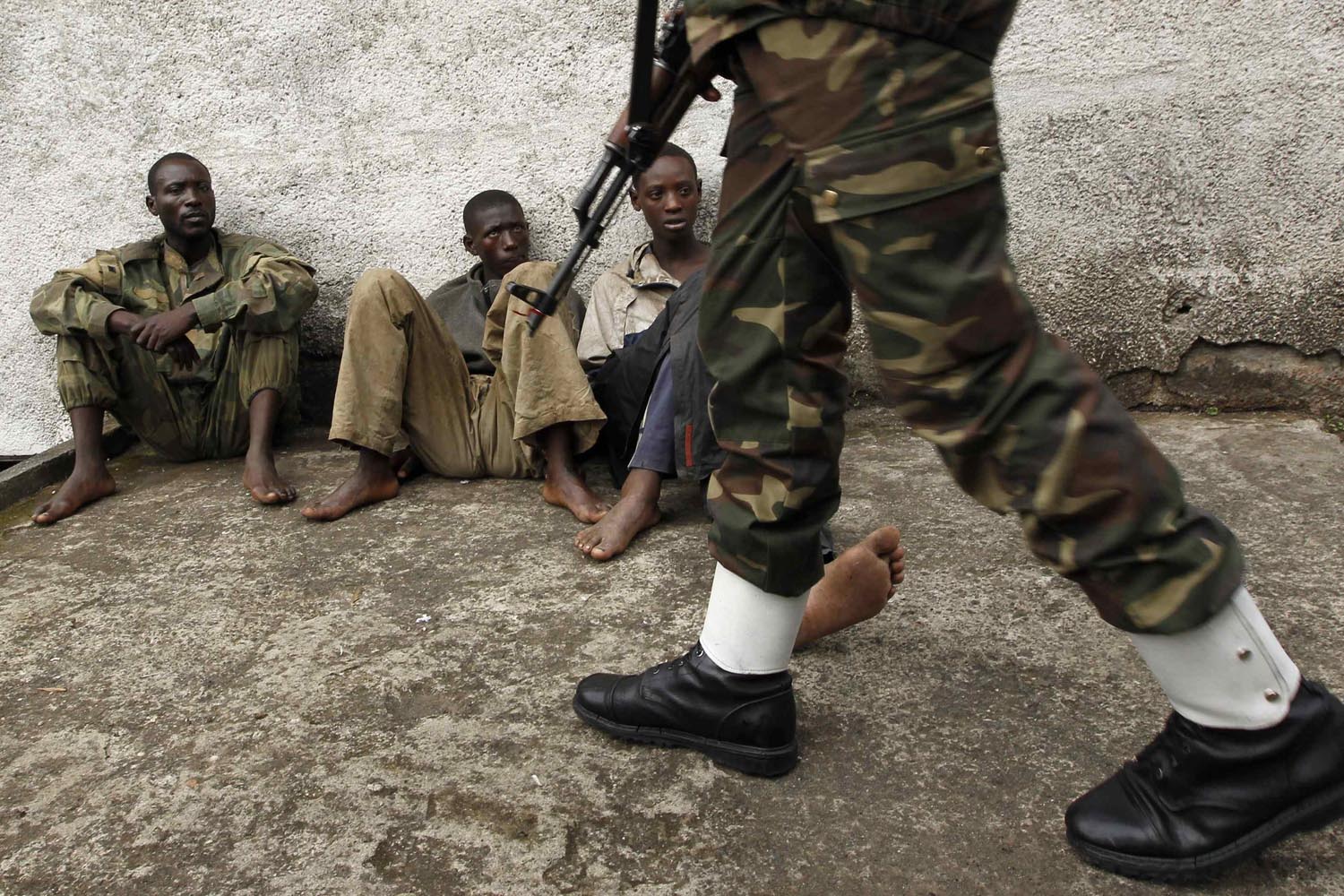 A Congolese soldier guards suspected rebels arrested during an operation against M23 rebels in Goma