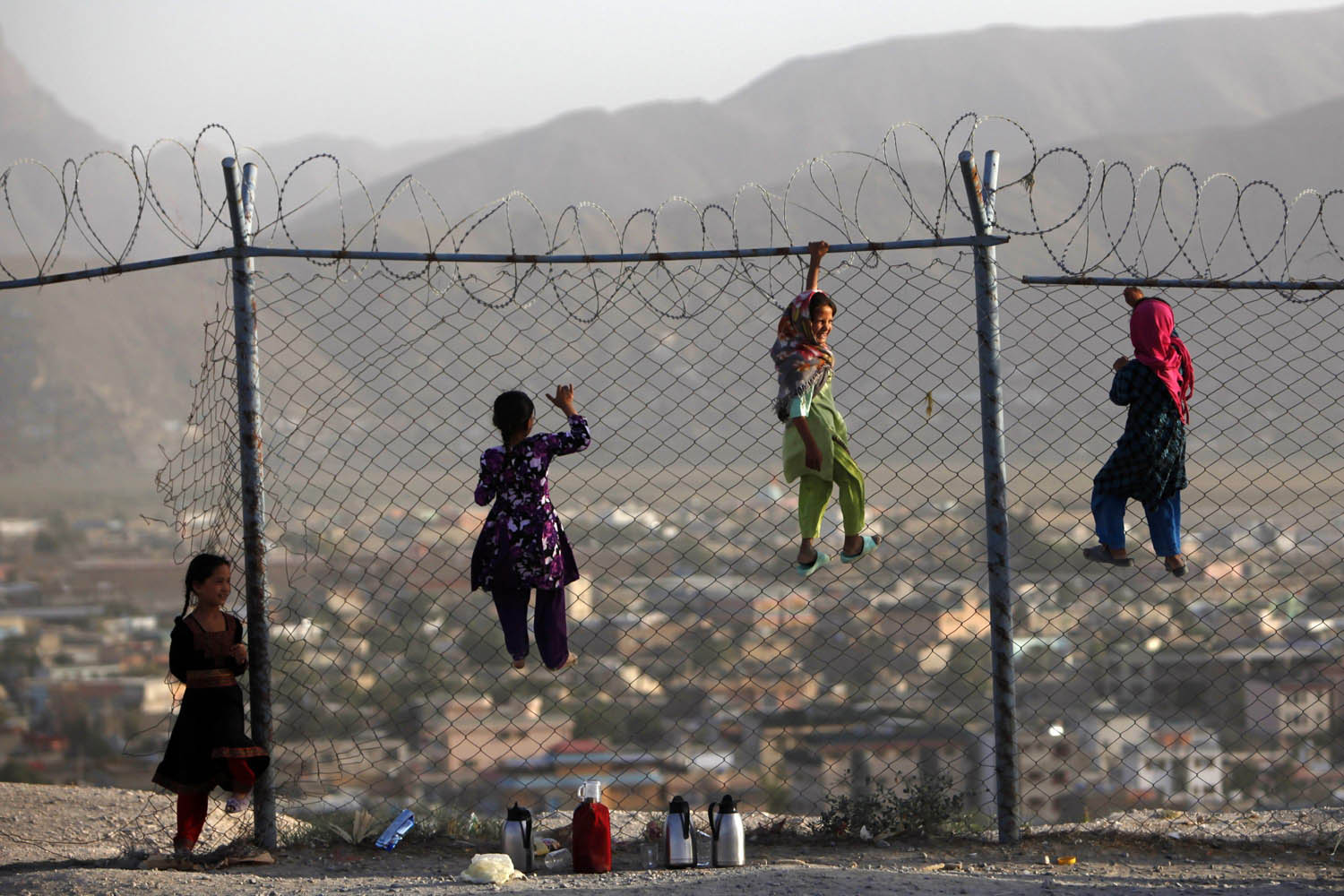 Afghan children climb onto a fence while playing as they sell tea in Kabul