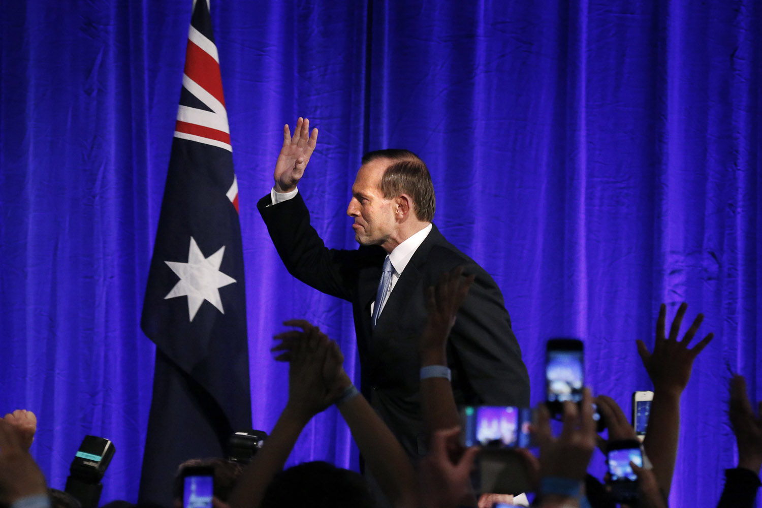 Australia's conservative leader Tony Abbott  gestures as he walks to the stage to claim victory in Sydney
