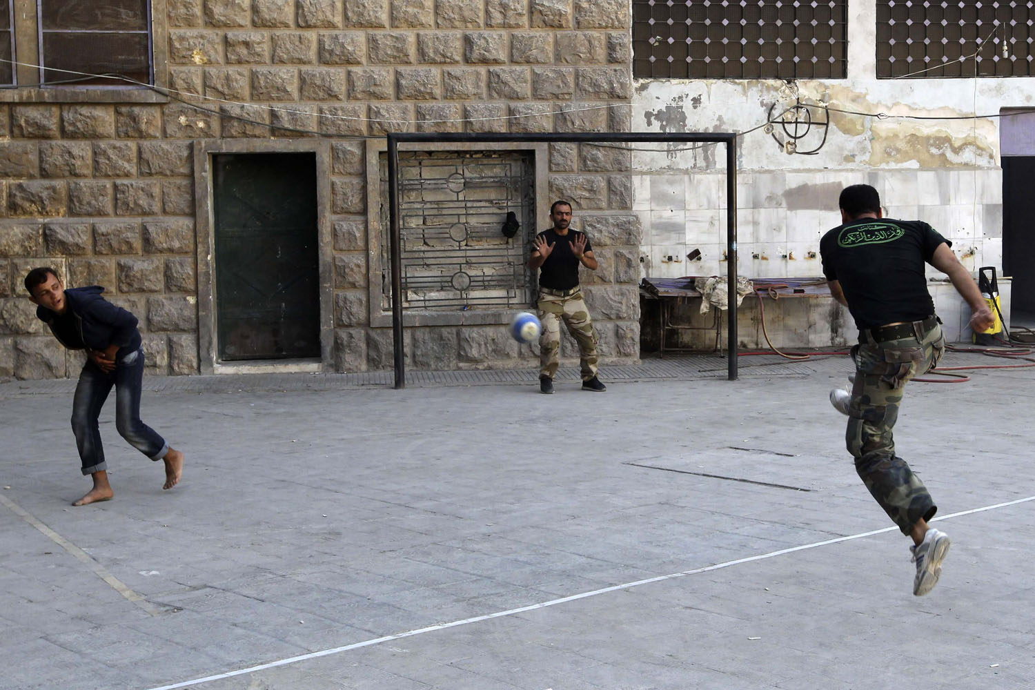 Free Syrian Army fighters play football in the Aleppo district of Salaheddine