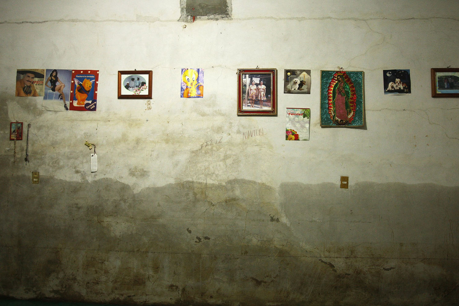 Pictures hang on a wall stained with water marks inside a house in San Cristobal Sola de Vega