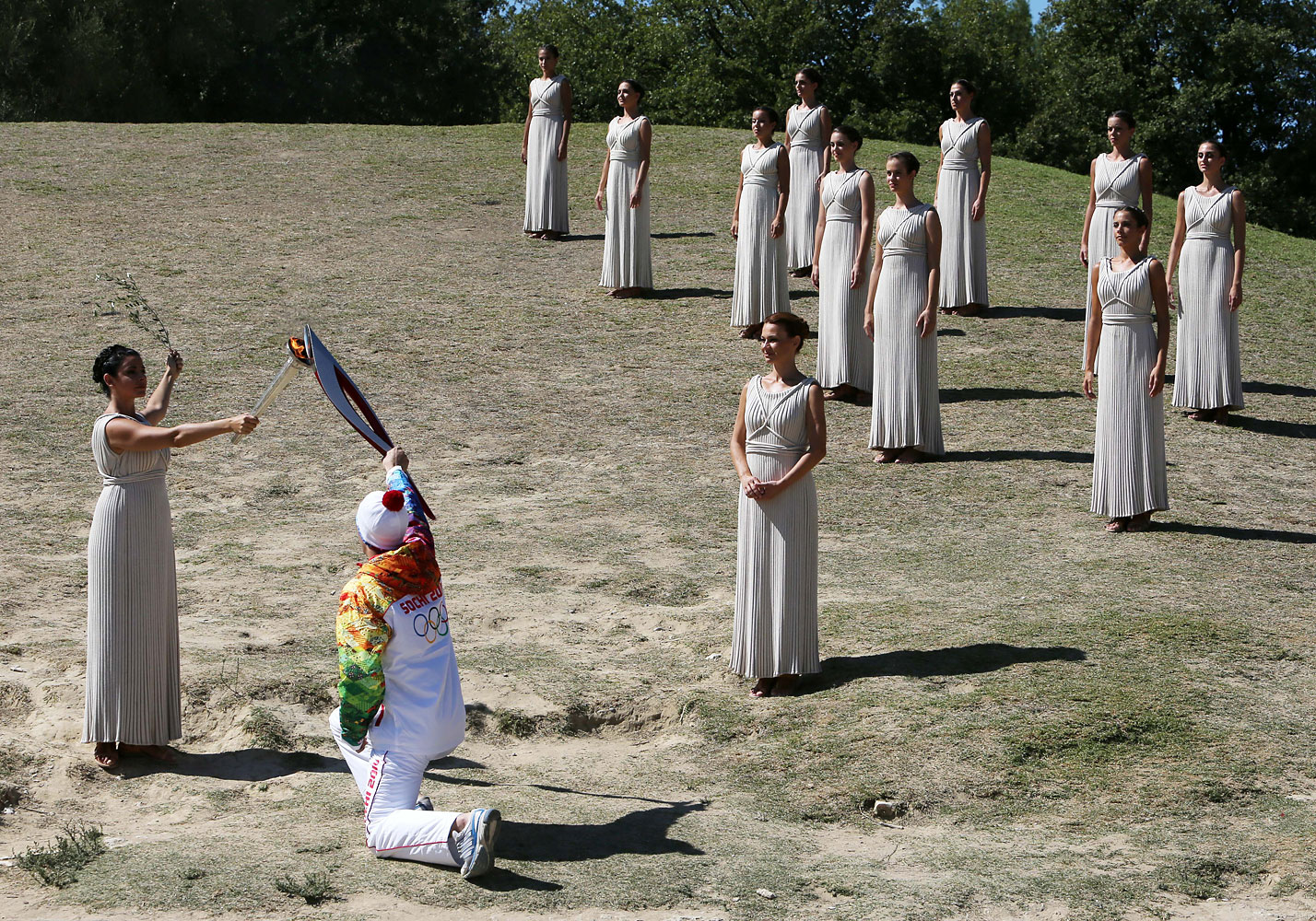 Actress Ino Menegaki as high priestess, left, passes the Olympic Flame to the first torch runner - Greek champion skier Giannis Antoniou - during the final dress rehearsal at Ancient Olympia, in west southern Greece.