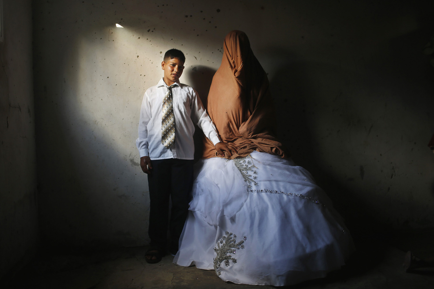 Palestinian groom Ahmed Soboh and his bride Tala stand inside Tala's house which damaged during Israeli strike in 2009, during wedding party in Beit Lahiya