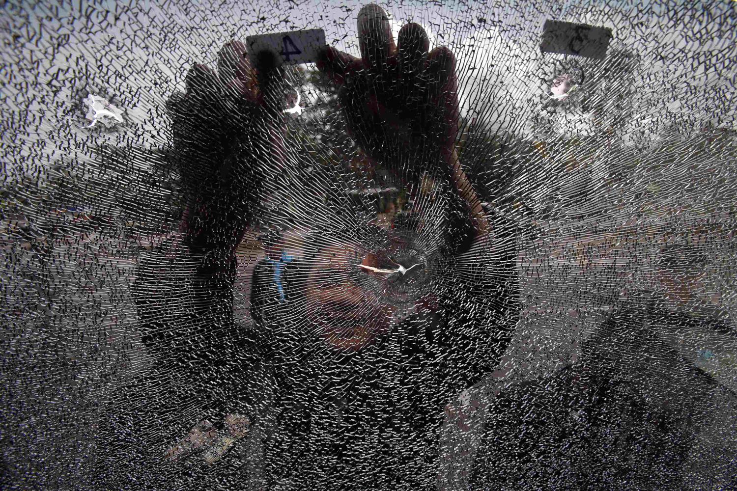 Police officer inspects the damaged windshield of a police bus after clashes between police and rubber farmers in Bangsaphan