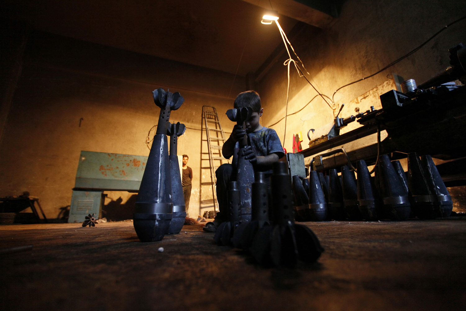 Issa assembles a locally handmade mortar shell in a weapons factory of the Free Syrian Army in Aleppo