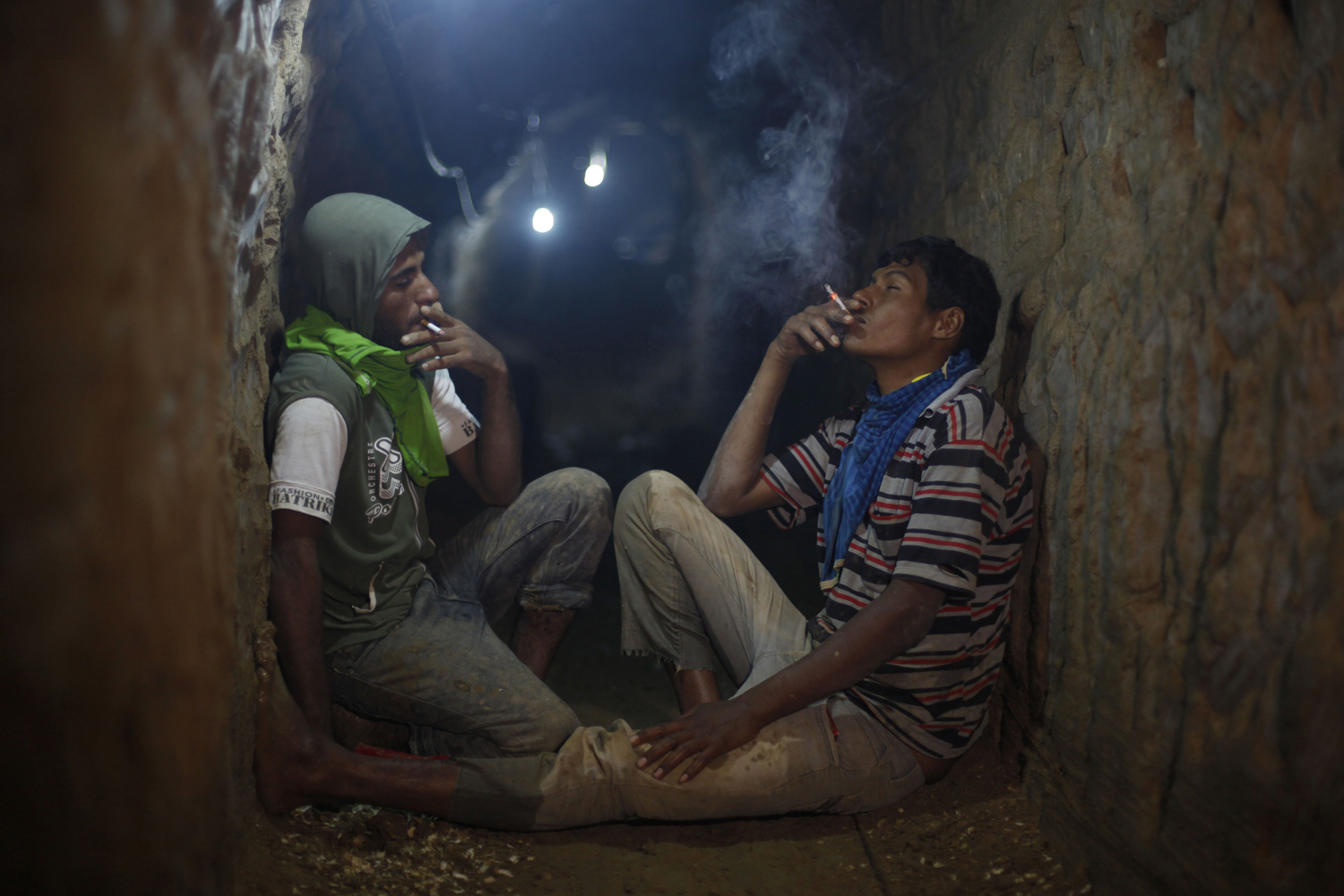 Palestinian tunnel workers smoke cigarettes as they rest inside a smuggling tunnel flooded by Egyptian security forces, beneath the Gaza-Egypt border in the southern Gaza Strip