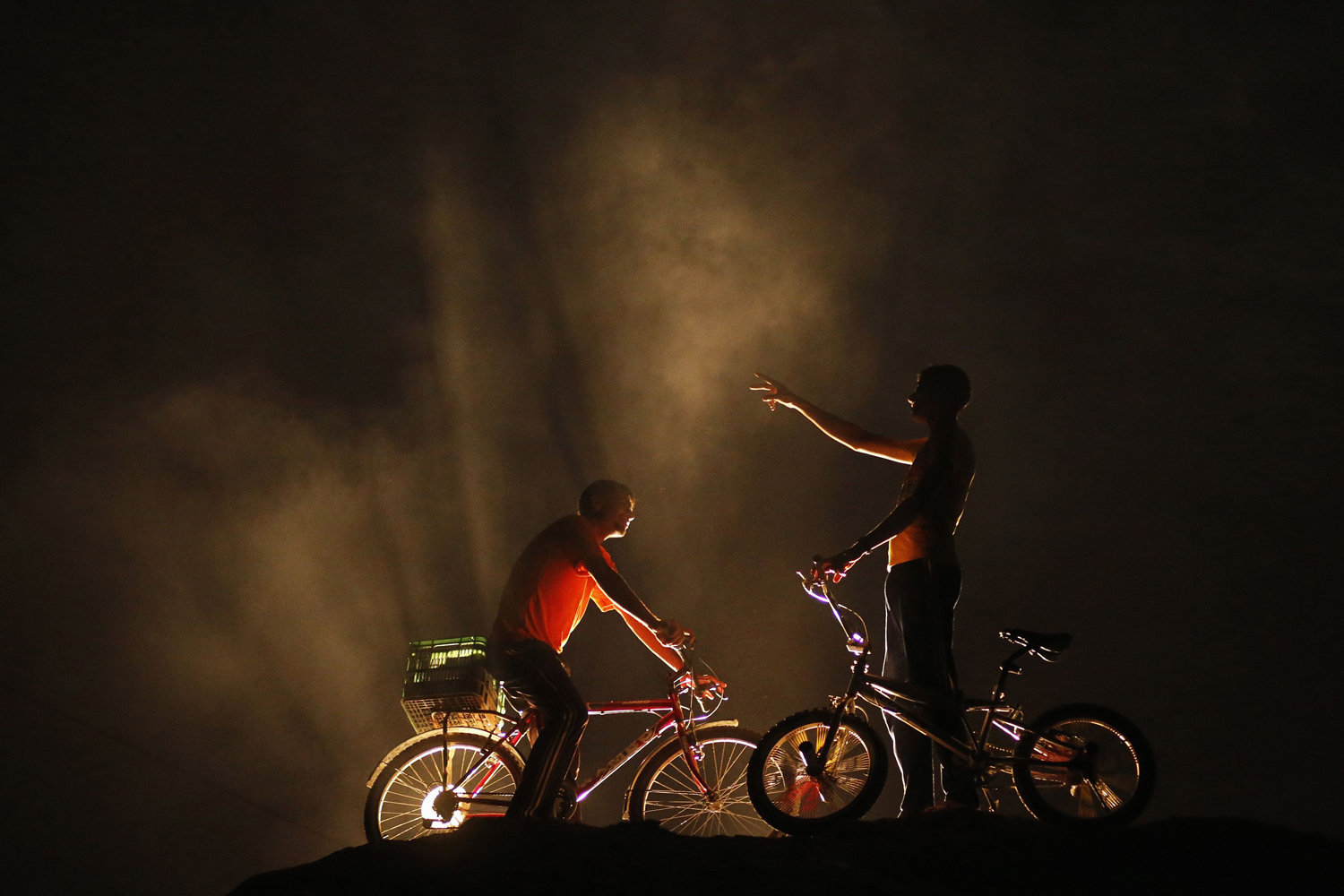 Palestinian boys stand with their bicycles on top of a sandhill near the beach in the northern Gaza Strip