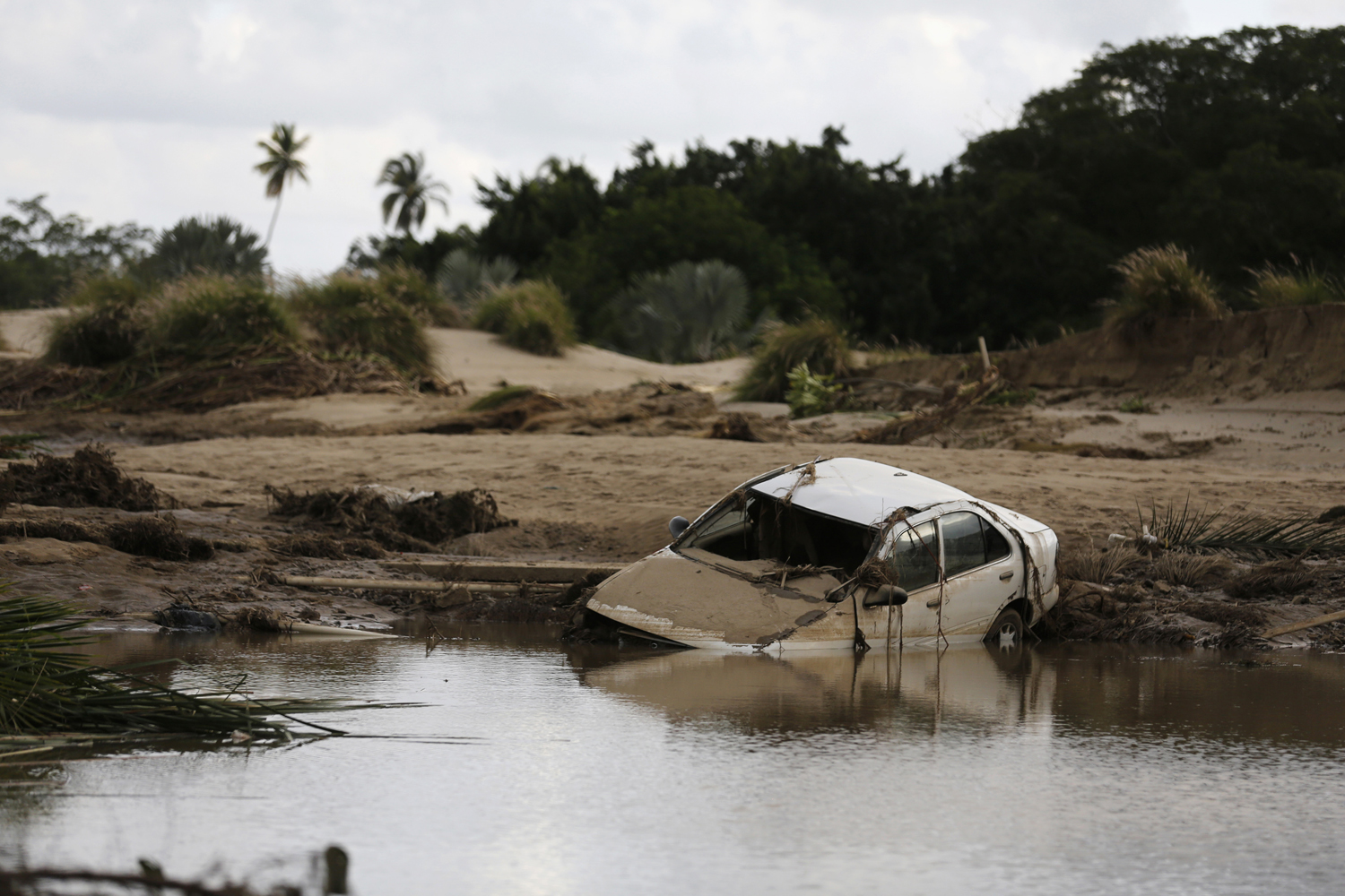 A car lies partially submerged in floodwater at the golf course of a hotel in the flooded Mexican beach resort of Acapulco