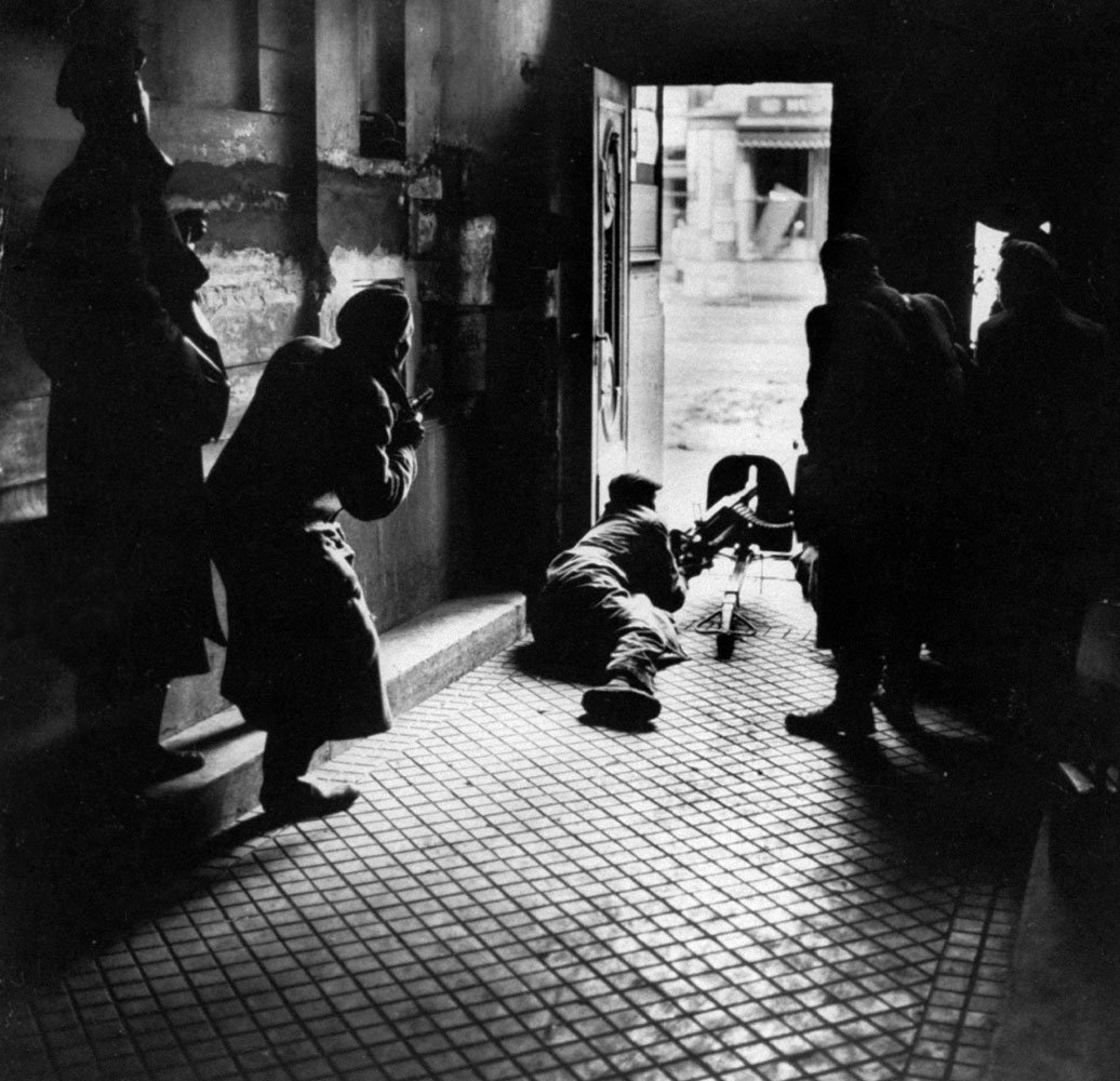 Caption from LIFE.  Firing at secret police, insurgents emplace old machine gun in a doorway on Rakoczi Avenue, where they had taken hasty refuge from police fusillade.