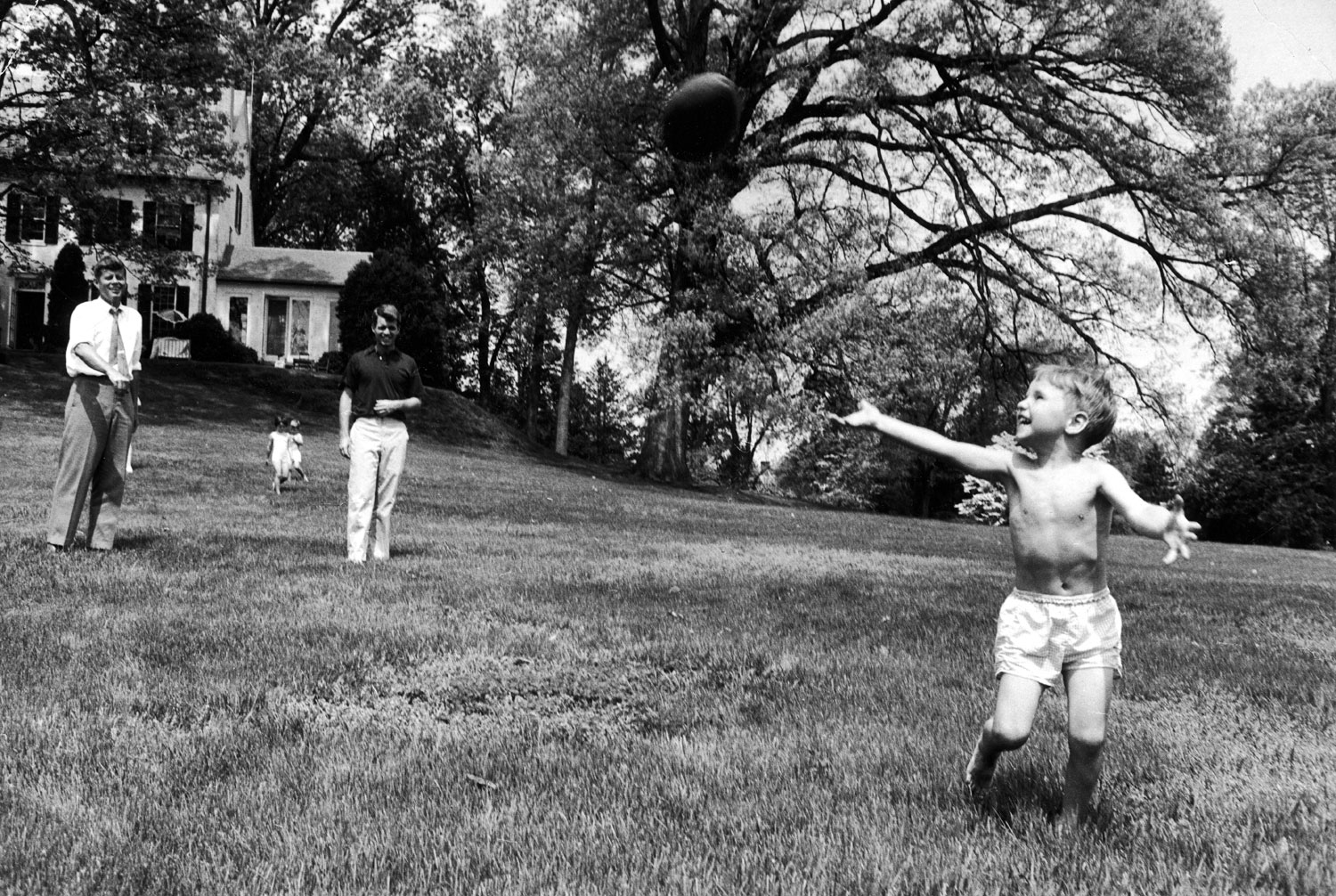 Sen. John Kennedy plays football with his nephew, Bobby Jr., at his brother Robert's Hickory Hill, Va., home, 1957.