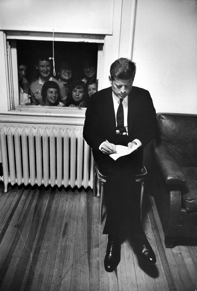 Senator John F. Kennedy checks over a speech at a stop during his presidential campaign, 1960.