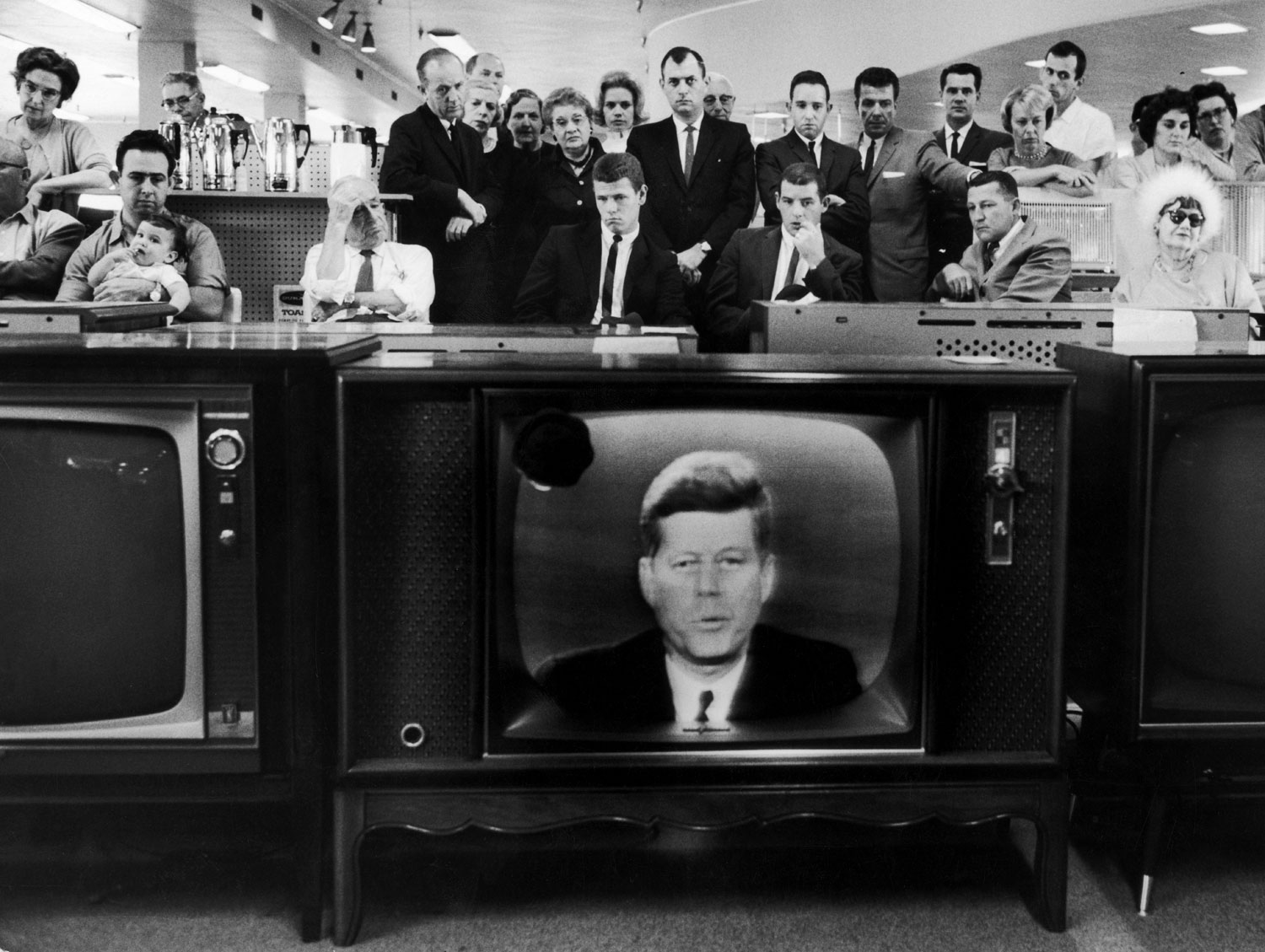 People in a department store watch as President John Kennedy announces a blockade of Cuba during the Cuban Missile Crisis, 1962.