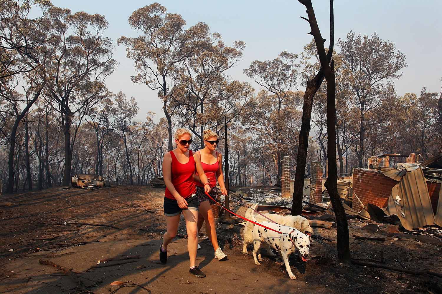 Oct. 21, 2013. Melissa White assists her sister Christie Daschke at her home destroyed by bushfire in Winmalee, Australia.