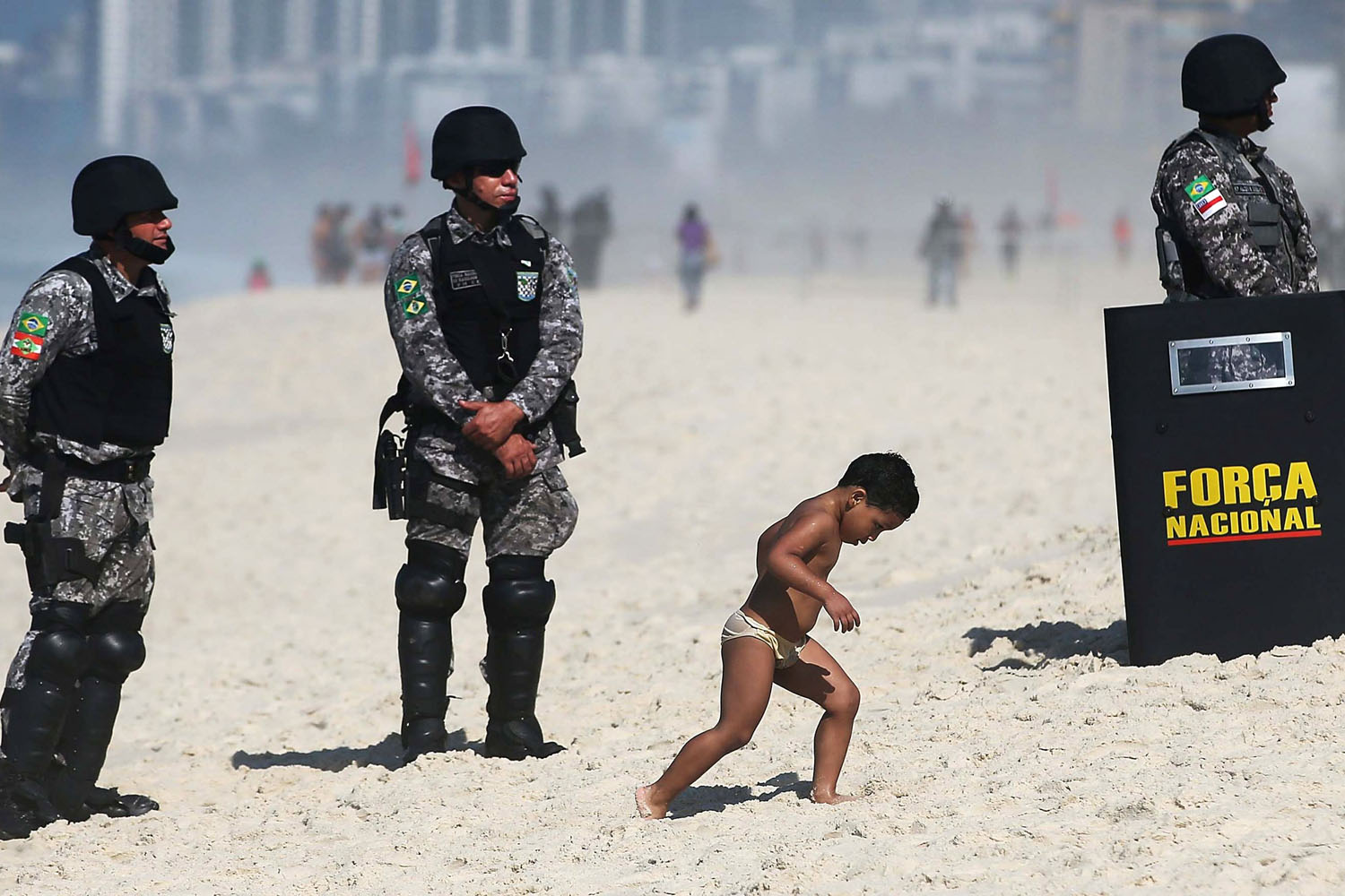 Oct. 21, 2013. A boy walks past military police standing guard outside the seafront Windsor Barra hotel before the start of an auction of one of the world's biggest offshore oil finds in Rio de Janeiro, Brazil.