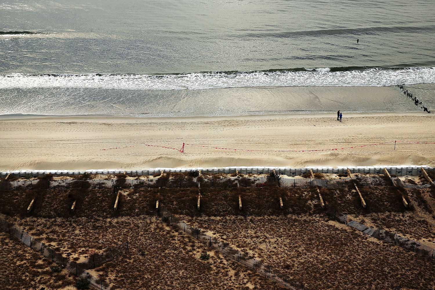 Oct. 22, 2013. People stand on a beach near the remains of the Rockaway boardwalk, damaged in Hurricane Sandy in the in Rockaway neighborhood of the Queens borough of New York City.