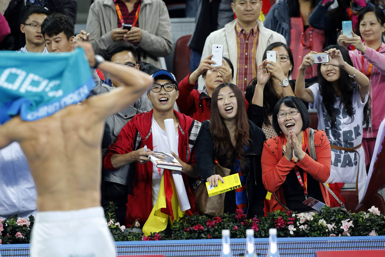 Fans watch Spain's Rafael Nadal change his shirt after he defeated Philipp Kohlschreiber of Germany in their match at the China Open tennis tournament in Beijing