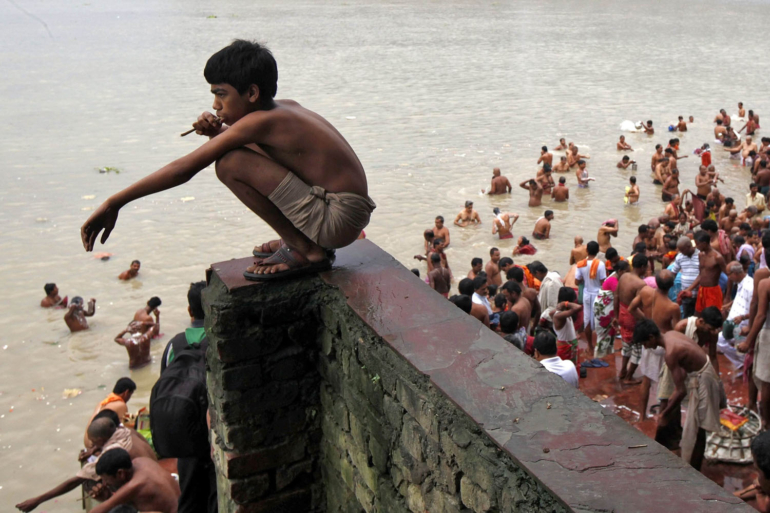 A Hindu boy brushes his teeth with a neem twig as others take a dip on the banks of the Ganges river on the holy day of "Mahalaya" in Kolkata