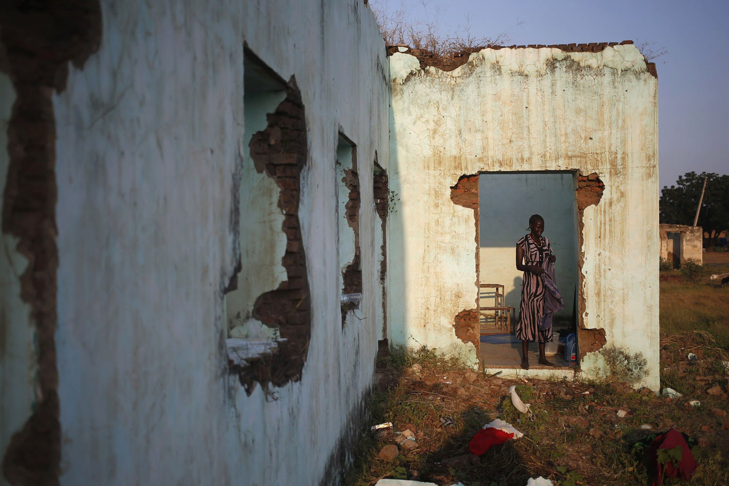 A woman stands in abandoned building as she dries washed clothes near polling stations in the town of Abyei