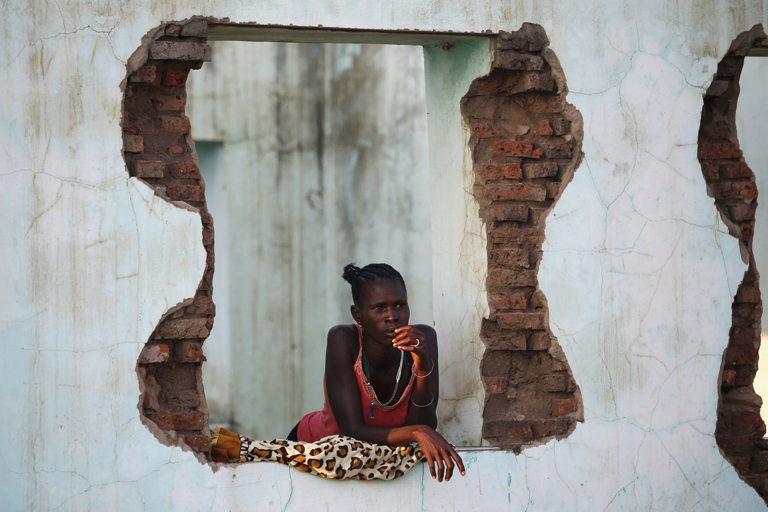 A woman looks out of an abandoned building near polling stations in the town of Abyei