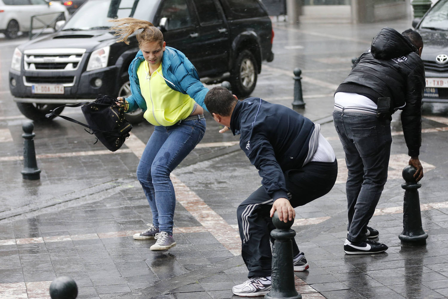 Oct. 28, 2013. A man helps a woman to cross a square during strong winds in central Brussels, Belguim.