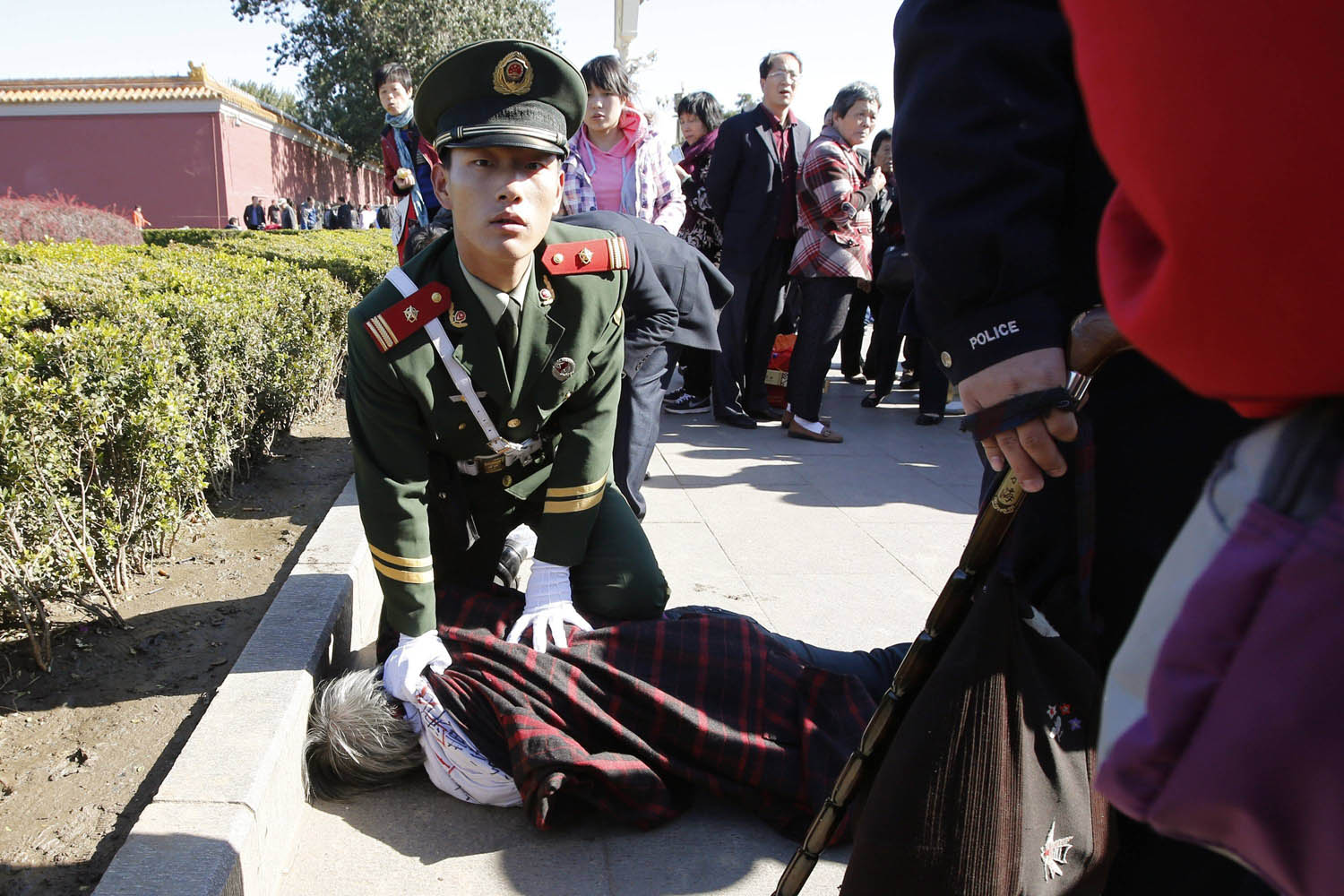 Oct. 29, 2013. A paramilitary policeman detains a woman who threw papers, believed to be her petition papers, near the main entrance of the Forbidden City in Beijing.