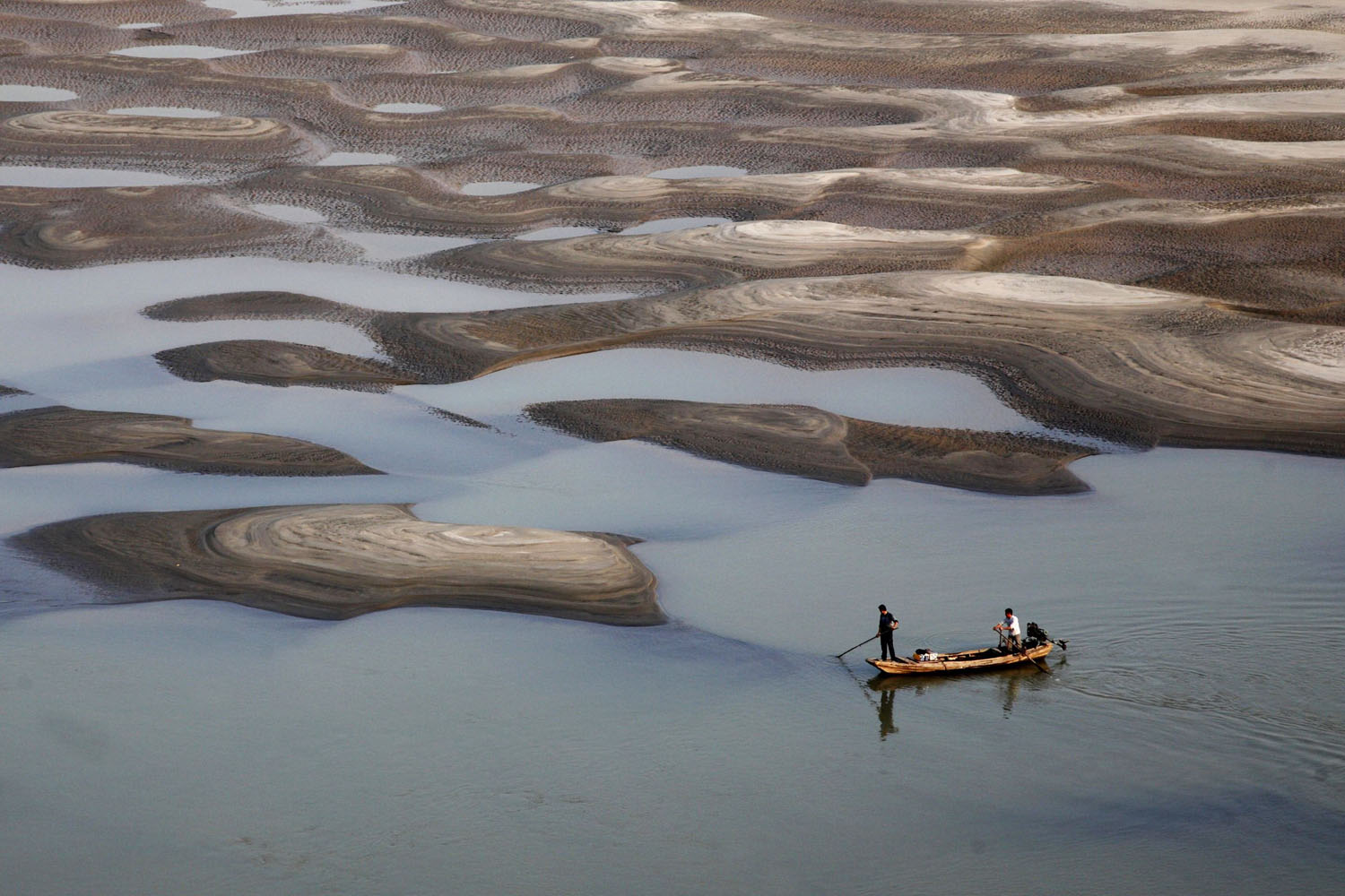 Oct. 27, 2013. Two men row a boat past a partially dried-up riverbed on a section of the Yangtze River in Jiujiang, Jiangxi province, China.