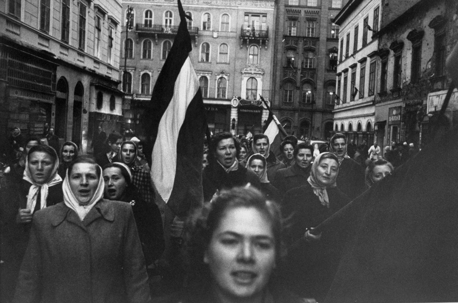 Caption from LIFE.  Carrying flags of old Hungary and singing a patriotic song, Budapest women march in honor of men who died fighting communists.