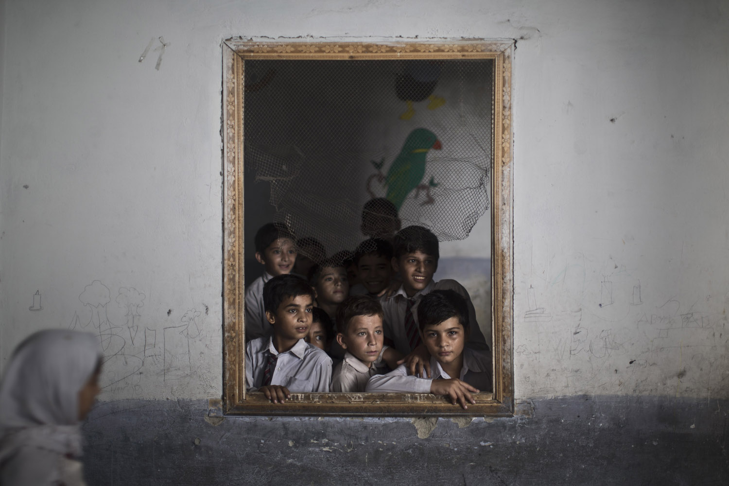 Oct. 9, 2013. Pakistani schoolboys look out the window of their classroom at other classmates chanting prayers to commemorate the anniversary of Malala's shooting by Taliban, at a school in Rawalpindi, Pakistan.