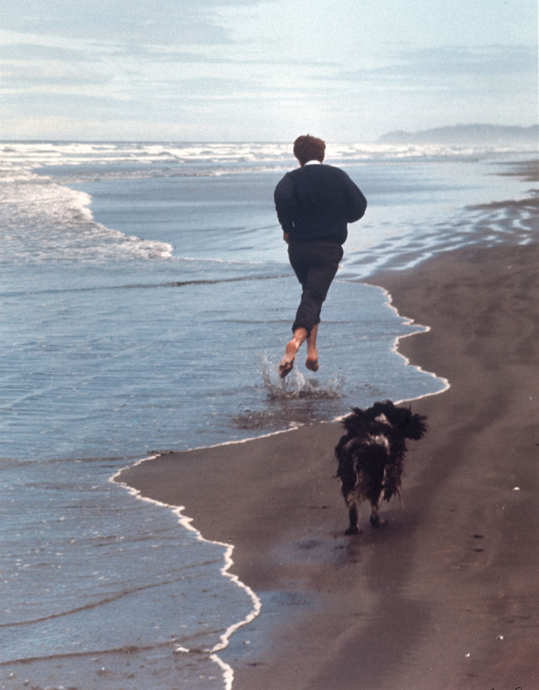 Presidential candidate Bobby Kennedy and his dog, Freckles, running on beach.