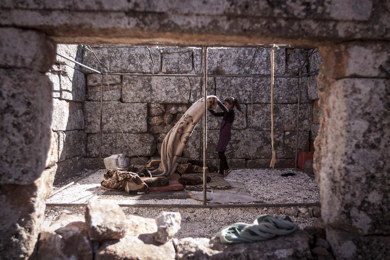 Sept. 27, 2013. A displaced Syrian girl makes her bed after waking up near Kafer Rouma, in ancient ruins used as temporary shelter by those families who have fled from the heavy fighting and shelling in the Idlib province countryside of Syria.