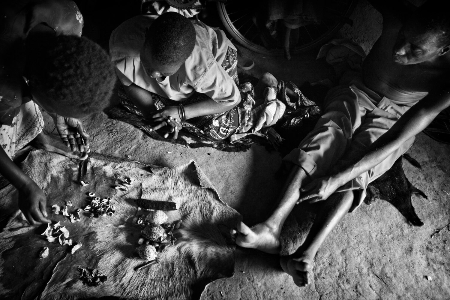A Witch Doctor diagnoses a patient with mental illness by reading the way pieces of bone and shell fall on a goats skin. Northern Uganda. March 2011.
