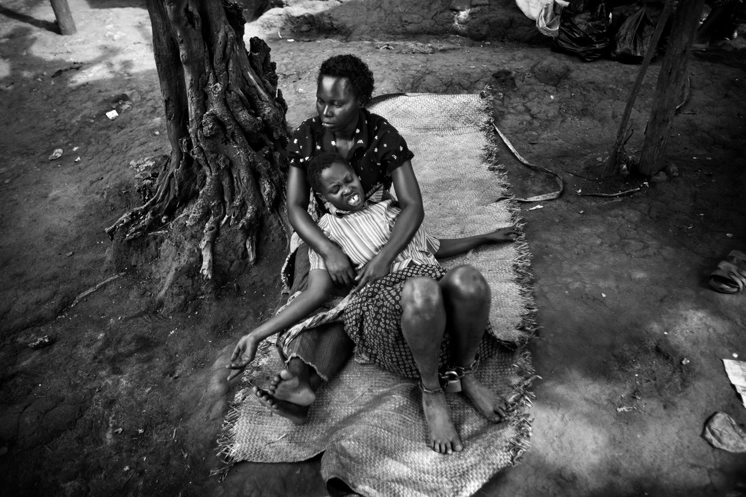 A chained patient awaits treatment at the clinic of a traditional healer. Kampala, Uganda. April 2011.