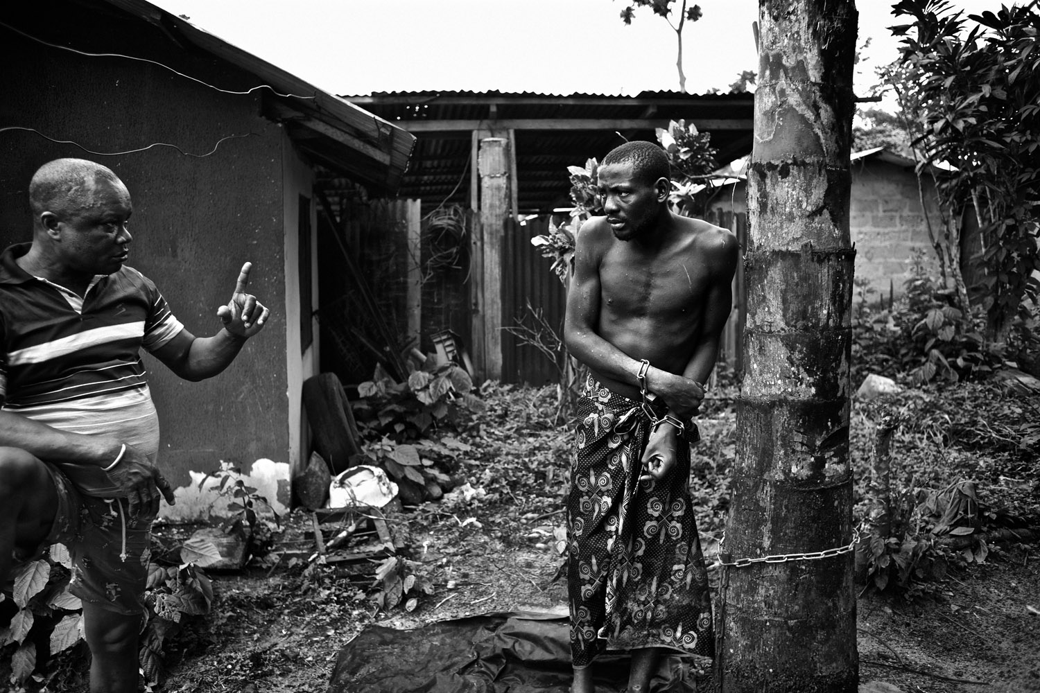 Native Doctor Lekwe Deezia claims to heal mental illness through the power of prayer and traditional herbal medicines. While receiving treatment, which can sometimes take months, his patients are chained to trees in his courtyard. They are not given shelter or protection from the elements and are visibly terrified of the doctor. The Niger Delta, Nigeria. October 2012.